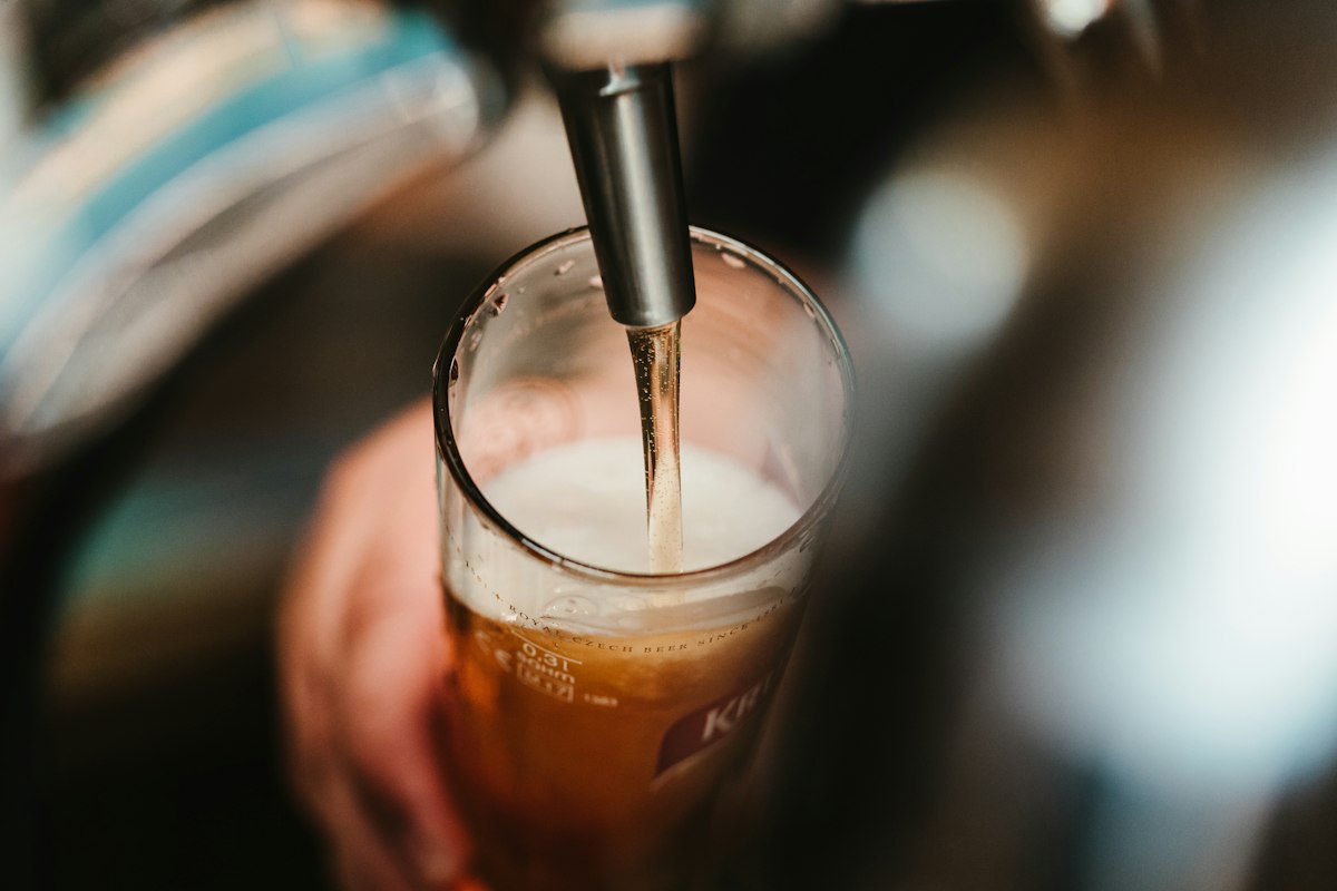 Frisch gezapftes Bier läuft vom Zapfhahn in das Glas an der Theke